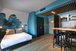 a bedroom with a bed and a kitchen with a bar at Appartements de la Cité - Saint-Malo in Saint Malo