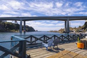 two chairs sitting on a dock near the water under a bridge at H - Cochito in Fort Bragg