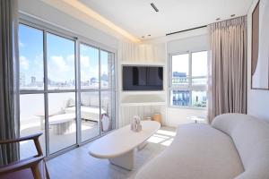 a living room with a couch and a large window at Allenby 36 Bauhaus Residence 5 Stars in Tel Aviv