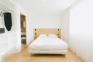 a white bedroom with a white bed and a mirror at Miranove in Montpellier