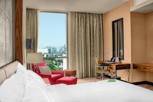 pokój hotelowy z łóżkiem, biurkiem i oknem w obiekcie Millennium Plaza Doha w mieście Doha