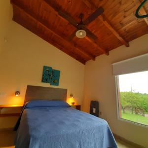 une chambre avec un lit et un ventilateur de plafond dans l'établissement Piscu Yaco, à Santa Rosa de Calamuchita