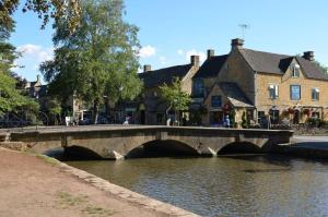 a bridge over a river with birds in the water at Clover Crest - 3-Bedroom House in Bourton on the Water