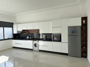 a kitchen with white cabinets and a washer at Luxury Terrace Apartment in Al Hoceïma