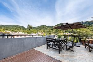 einen Tisch und Stühle mit Sonnenschirm auf dem Balkon in der Unterkunft Mutianyu Great Wall Jingshan First House Boutique B&B in Mutianyu Village