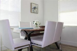 a dining room table with white chairs and a laptop at Single family house in Long Beach