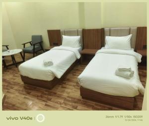 a room with two beds and a table and a chair at The Grand Inn Resort in Dum Duma