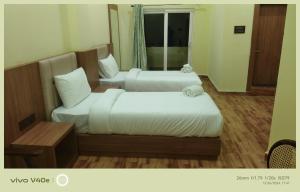 two twin beds in a room with a window at The Grand Inn Resort in Dum Duma +7 photos