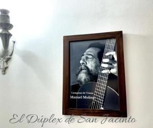 un'immagine di un uomo che suona la chitarra su un muro di El Dúplex de San Jacinto a Siviglia