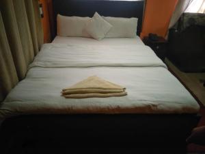 加德满都Suhan hotel的一张带白色床单的床和两张折叠毛巾