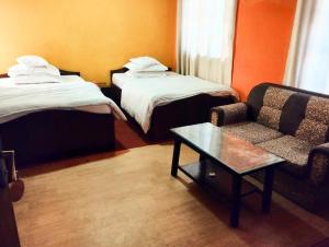 加德满都Suhan hotel的一间配有两张床、一张沙发和一张桌子的酒店房间