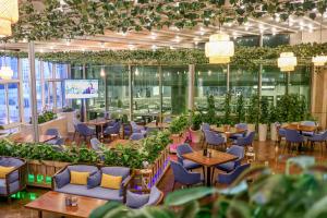 restauracja ze stołami, krzesłami i roślinami w obiekcie Millennium Plaza Doha w mieście Doha