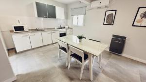a kitchen with white cabinets and a table and chairs at Soltigua Apart Hotel Mendoza in Mendoza