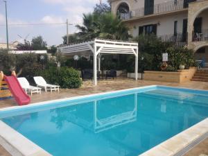 een zwembad met een witte pergola naast een huis bij Villa Ceni - Appartamenti con camere, cucina, wc e terrazza sul mare in villa con piscina, giardino e parcheggio in Marinella di Selinunte
