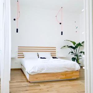 a bedroom with a white bed with a wooden headboard at M4 WHITE Monolocale Moderno e Funzionale in Scandicci