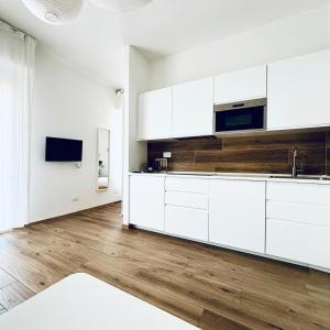 a kitchen with white cabinets and a wooden floor at M4 WHITE Monolocale Moderno e Funzionale in Scandicci