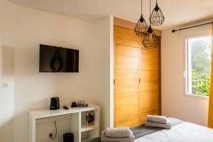 a bedroom with a bed and a television on the wall at Comme une évidence in La Chapelle aux Pies