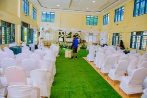 a room with white chairs and a man standing in the aisle at Centre Missionnaire Lavigerie in Kigali