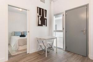 een witte kamer met een tafel en een bed bij Menaleka's House 7 in Málaga
