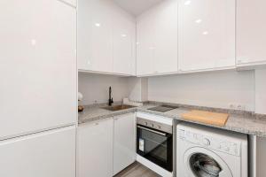een keuken met witte kasten en een wasmachine en droger bij Menaleka's House 7 in Málaga