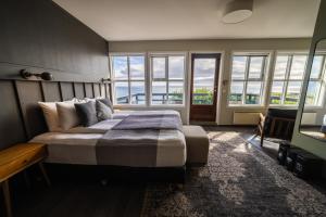 um quarto com uma cama grande e janelas em Fosshotel Hellnar em Hellnar