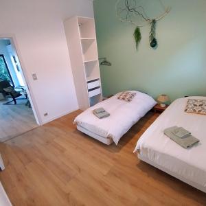 two beds in a room with wooden floors at Charmant Cottage in Châtenois