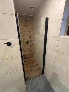 a bathroom with a shower with a wooden wall at Skrzynia in Skrzynia +13 photos
