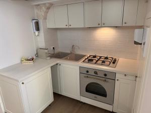 a white kitchen with a stove and a sink at Dimora Al Nonnino in Noci