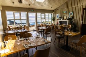 um restaurante com mesas, cadeiras e janelas em Fosshotel Hellnar em Hellnar