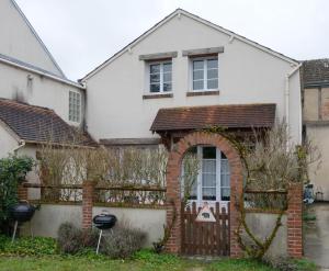 a house with an archway in front of a fence at La Petite Maison au calme - 2 chambres - à 200m des Bords de Loire in Saint-Jean-de-Braye