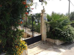 a black iron gate with a bunch of flowers at Villa Ceni - Appartamenti con camere, cucina, wc e terrazza sul mare in villa con piscina, giardino e parcheggio in Marinella di Selinunte