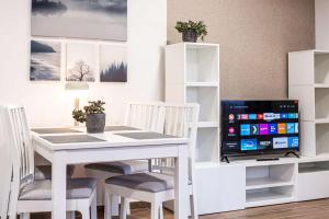a dining room with a white table and a television at Apartmán NORA in Šonov