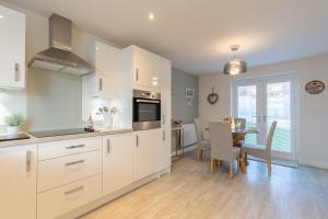 a kitchen with white cabinets and a table and a dining room at Foxglove Haven- 3-Bed Detached - Garden - Drive in Longridge
