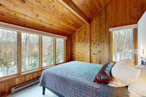 a bedroom with wooden walls and a bed and windows at Mad River Masterpiece in Irasville