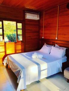 a bedroom with a large white bed with wooden walls at Caminhos da Serra do Tabuleiro - Chalé Araucária in São Bonifácio