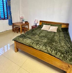 a bedroom with a bed with a green comforter and a table at Ta Phin Stone Mountain Homestay in Sa Pa