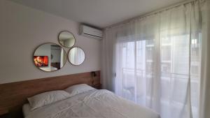 a bedroom with a bed and a mirror and a window at GROVE-City Center Apartment with free parking in Kragujevac