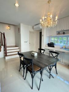 einen Esstisch mit Stühlen und einem Kronleuchter in der Unterkunft PY house khaoyai in Khanong Phra