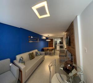a living room with a couch and a blue wall at Guarapari Bacutia Peracanga an9 in Guarapari