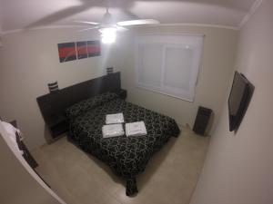 Dormitorio pequeño con cama y TV en De Sol A Sol en Monte Hermoso