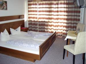 a bedroom with a bed and a chair and a window at Hotel Sonnhof in Wiesing