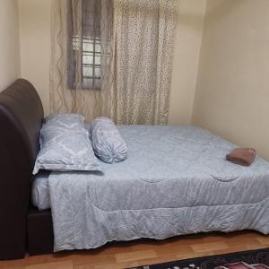 un letto con un piumone blu e una finestra di Homestay Lavender a Kajang