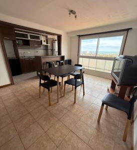 een woonkamer met een tafel, stoelen en een televisie bij Estrada Depto con Vista al Mar, 4 Ambientes in Mar del Plata