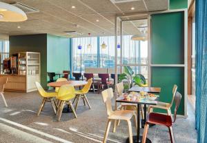 a dining room with tables and chairs and windows at B&B HOTEL Marne-la-Vallée Val d'Europe in Serris