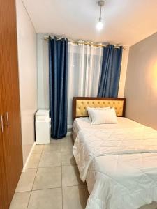 a bedroom with two beds and blue curtains at Residence Next Door Coral Mega in Kiambu