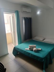 a bedroom with a bed with a green blanket and a window at Magnolia Guest House in St. Julianʼs