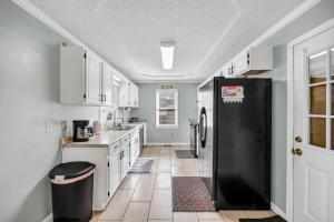 a kitchen with white cabinets and a black refrigerator at Sawgrass Cottage 3BR w Deck in Columbia