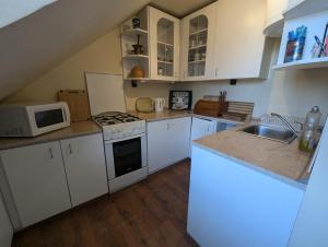 a kitchen with white cabinets and a stove top oven at Family Apartman by Budapest in Göd