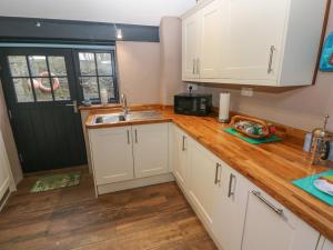 a kitchen with white cabinets and a wooden counter top at Stable Cottage in Pembroke +8 photos