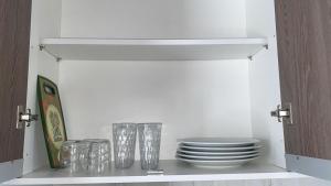a cabinet with plates and glasses on a shelf at Casa Aeroporto Premium Conforto e Conveniência para Sua Estadia in Campo Grande